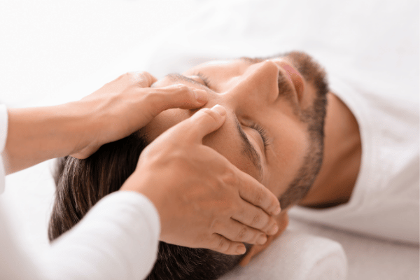 A man undergoing a head massage highlighting relaxation and self-care in a peaceful setting.