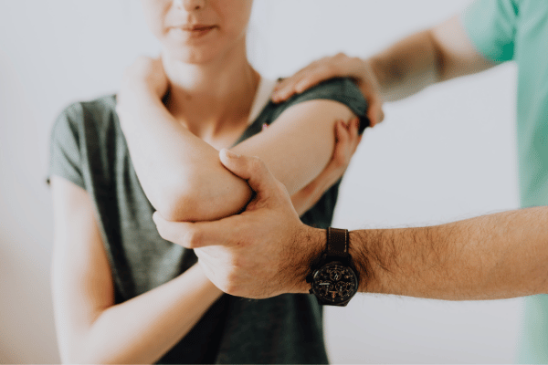 A man supports a woman’s arm as part of her rehabilitation and personal training program.