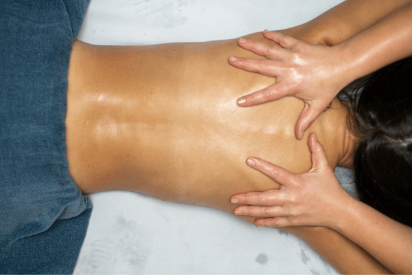 A woman enjoying a Swedish massage, with a therapist applying pressure to her back for relaxation.